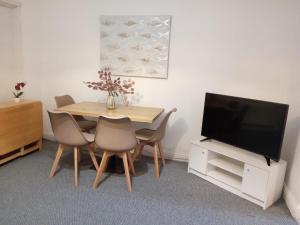 a dining room with a table with chairs and a television at Hallam Homestyle relocators and contractors in Walkley