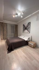 1 dormitorio con 1 cama y suelo de madera en Luxe Appartments on Stepnoy en Karagandá