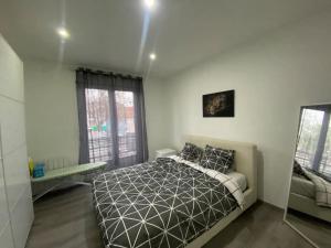 a bedroom with a bed and a large window at Le confort d'un appartement in Schiltigheim