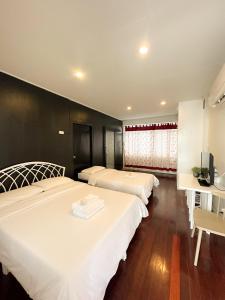 1 dormitorio con 2 camas y escritorio con TV en White Lodge Hotel Bangkok, en Bangkok