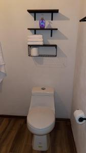 a bathroom with a toilet and a shelf with towels at Cabaña Beto’s in Mazamitla