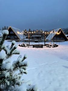 einen schneebedeckten Park mit Bänken und Pavillons in der Unterkunft Treeline Cabins in Cădăreşti