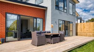 a patio with a table and chairs on a deck at Amazing the Waikato River-View Brand New Villa with 4 bedrooms in Hamilton