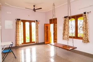an empty room with windows and a ceiling fan at Prabas - Farm house in Puducherry