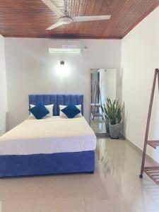 a bedroom with a blue bed with blue pillows at New White House in Aluthgama