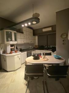 a kitchen with white cabinets and a table and chairs at The A project, Deluxe Suites in Agria +4 photos