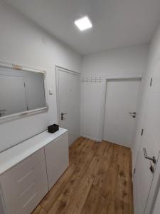 a bathroom with white cabinets and a large mirror at Apartman Aura Prijedor in Prijedor