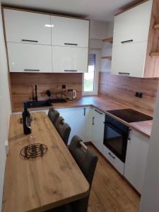 a kitchen with a wooden table and white cabinets at Apartman Aura Prijedor in Prijedor