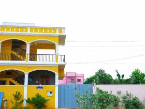 a yellow house with a blue fence in front of it at Prabas - Farm house in Puducherry