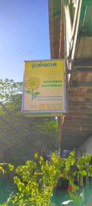 Ein Schild hängt von einem Gebäude neben einigen Pflanzen in der Unterkunft Sunflower Guesthouse Koh Rong in Phumĭ Kâoh Rŏng