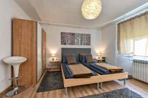 a bedroom with a bed with blue sheets and a chandelier at Apartman Jura, dvije spavaće sobe in Sveti Ivan Zelina