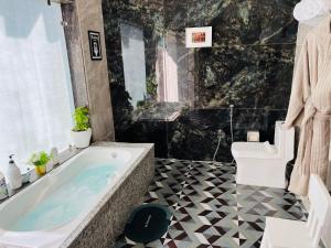 a bathroom with a large tub and a black and white floor at Jewel of Jungle in Tāla
