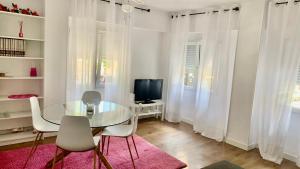 a dining room with a glass table and chairs and a television at Casa Bia Plus in Elche