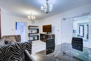 a living room with a glass table and a television at Charming 7 bedroom house sleeps up to 13 guests in Romford
