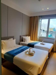 2 bedden in een hotelkamer met een raam bij pristinehotel in Manilla