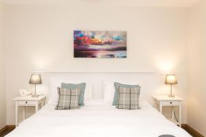 a bedroom with a white bed with two tables at Fleet View in Gatehouse of Fleet