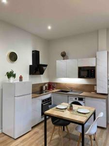 a kitchen with a table and a kitchen with white cabinets at Logement entier-Clim-100%équipé-Hypercentre-Balcon in Brive-la-Gaillarde