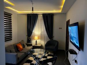 a living room with a couch and a tv at Karjel Homes Apartments in Sunyani