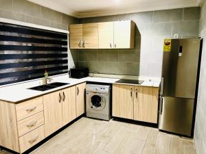 a kitchen with a refrigerator and a washing machine at Karjel Homes Apartments in Sunyani