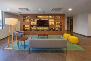 uma sala de estar com um sofá e cadeiras e uma televisão em City Express by Marriott Tlalnepantla em Cidade do México