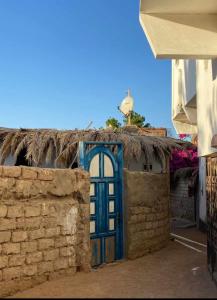 House with backyard in dahab في دهب: باب أزرق على جانب مبنى من الطوب