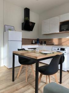 a kitchen with a wooden table and two chairs at Appartement hypercentre 100% équipé *Clim* in Brive-la-Gaillarde