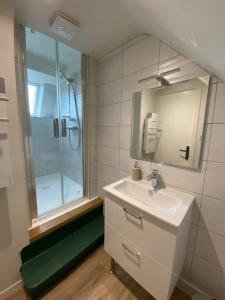 een witte badkamer met een wastafel en een douche bij Appartement chaleureux - Clim réversible - Meublé A-Z in Brive-la-Gaillarde