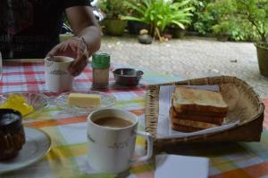 a table with a basket of bread and a cup of coffee at Bella Homestay Kerala in Alleppey