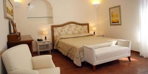 a bedroom with a bed and a white chair and a chair at Palazzo Iaquinto in Santa Maria di Castellabate