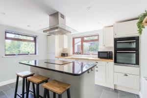 una cocina con armarios blancos y una isla con taburetes en Home in Llanberis, en Llanberis
