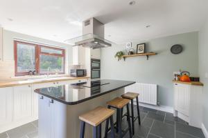 una cocina con armarios blancos y una barra con taburetes en Home in Llanberis, en Llanberis