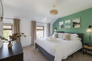 Home in Llanberis في لانبيريس: غرفة نوم بسرير ابيض كبير وجدران خضراء