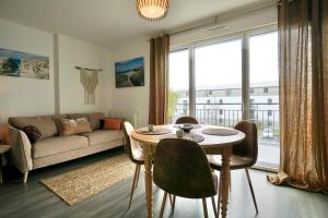 ein Wohnzimmer mit Tisch und Stühlen und einer Couch in der Unterkunft Les sables blancs*50m de la mer* in Concarneau