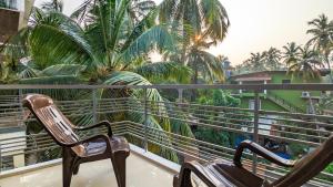 two chairs sitting on a balcony with palm trees at Poolside Paradise 1Bhk Luxury Apartment in Siolim. in Siolim