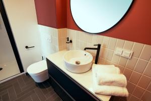 a bathroom with a sink and a toilet and a mirror at B85 Suites in Warsaw