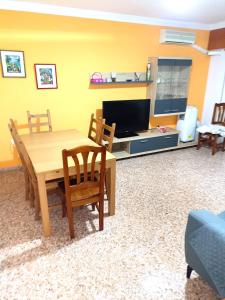 uma sala de estar com uma mesa de madeira e uma televisão em Cómodo alojamiento muy cerca de la playa em El Perellonet