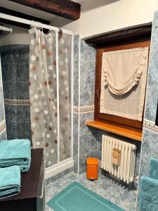 La salle de bains est pourvue d'une douche, d'une fenêtre et de serviettes. dans l'établissement Jolie Maison Aosta Centro, à Aoste