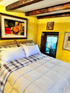 - une chambre avec un grand lit aux murs jaunes dans l'établissement Jolie Maison Aosta Centro, à Aoste