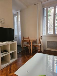 a living room with a table and a tv at Palais Ophelia in Nice