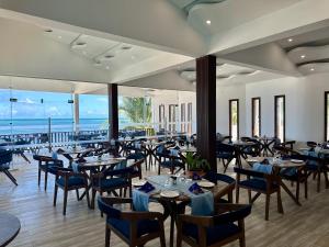 a restaurant with tables and chairs and the ocean at Dream of Zanzibar Resort & Spa - Premium All Inclusive in Uroa