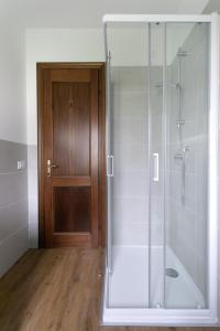 a bathroom with a glass shower with a wooden door at WoodenKey Asiago bicamere immerso nel verde in Asiago
