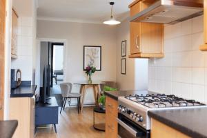 a kitchen with a stove and a table in it at The Leyton Midland Crib - Cozy 2BDR Flat with Study Room + Garden in London