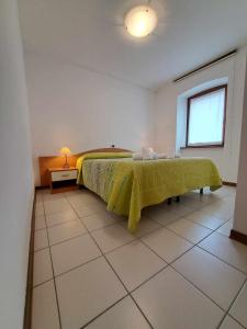 a bedroom with a bed with a green blanket on it at Albergo Martina in Chiusaforte