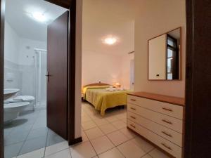uma casa de banho com um quarto com uma cama e um lavatório em Albergo Martina em Chiusaforte