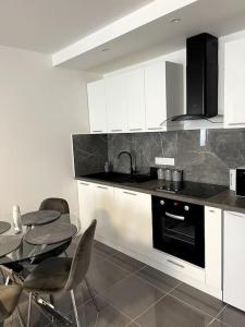 a kitchen with white cabinets and a table with chairs at Savigny-le-Temple : Magnifique suite avec jacuzzi in Savigny-le-Temple