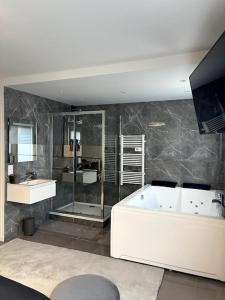 a large bathroom with a tub and a sink and a tub at Savigny-le-Temple : Magnifique suite avec jacuzzi in Savigny-le-Temple