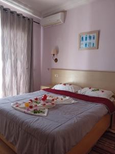 Hôtel Romane في الحمامات: غرفة فندق فيها سرير عليه ورد