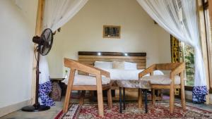 a bedroom with a bed and two chairs and a table at Haradali's Home in Arusha