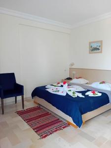 a bedroom with a bed with a blue blanket and a chair at Hôtel Romane in Hammamet