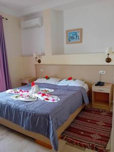 a bedroom with a bed with two plates of food on it at Hôtel Romane in Hammamet